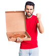 © Krakenimages.com - Young handsome man with beard holding delivery cardboard with italian pizza annoyed and frustrated shouting with anger, yelling crazy with anger and hand raised