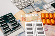 © GraysonStock - a group of medicines, pills, blister packs, next to Brazilian reais banknotes, on a white background, high prices in medicines and expenses in medicine and treatments.