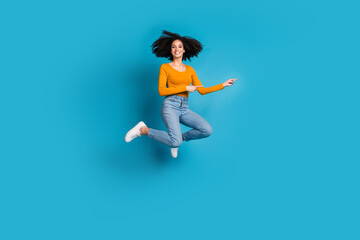 Sticker - Full body photo of attractive young woman jumping point empty space dressed stylish yellow clothes isolated on blue color background