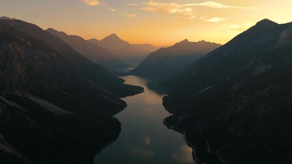 Wall Mural - Breathtaking aerial view of Lake Plansee in Tyrol, Austria at sunset, highlighting the majestic mountains.