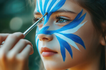 Poster - Close-up of children's face painting artist drawing blue and white paint on the forehead