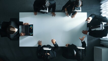 Top down aerial view of professional business team wear vr headset to enter virtual world while sitting and using hand gestures to manipulate the data from the manager laptop. Technology. Directorate.