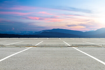 Wall Mural - Empty parking lot against beautiful landscape on sunset sky.