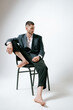 © Elina Leonova - Handsome man, fashion model sits on chair, barefoot