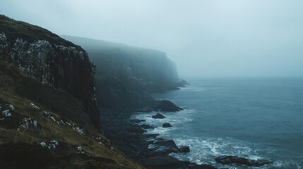 Sticker -   A hazy morning on a cliff overlooking water with rocks below