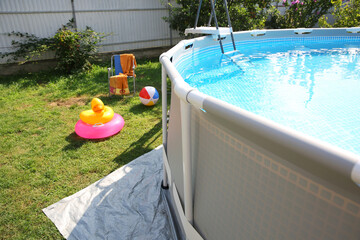 Poster - Above ground swimming pool, folding chairs, towel, inflatable rings and ball in backyard