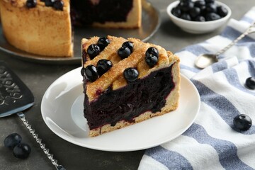 Slice of delicious homemade blueberry pie served on grey table, closeup