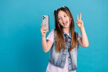 Wall Mural - Photo portrait of charming little girl selfie photo v-sign wear trendy jeans outfit isolated on blue color background