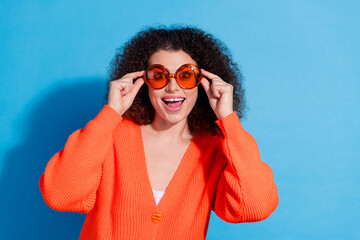 Wall Mural - Photo portrait of curly chevelure hair latin model woman tourist wearing stylish sunglasses isolated on blue color background