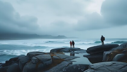 The magnificent view of the seaside, two tourists stand on the rocks, with the stormy waves and the cloudy sky in the distance, bringing a mysterious and tranquil feeling.