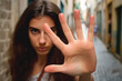 © JepaesSaums - A woman's assertive hand gesture saying 'stop,' signaling her defiance against harassment.