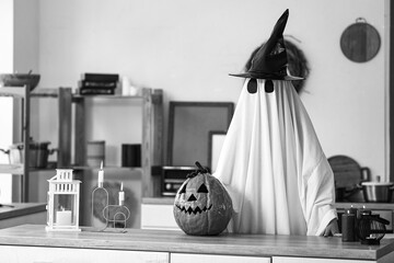 Sticker - Person in Halloween costume of ghost with carved pumpkin and witch hat at home