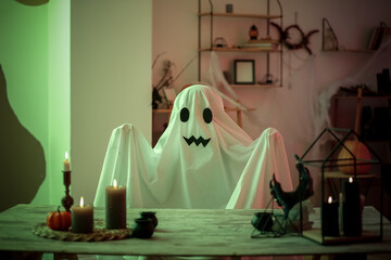 Sticker - Person in Halloween costume of ghost with burning candles at home