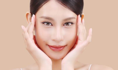 Close up face of beautiful young Asian woman with K beauty style makeup and perfect skin on isolated beige brown background. Facial and skin care concept for commercial advertising.