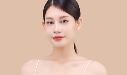 Close up face of beautiful young Asian woman with K beauty style makeup and perfect skin on isolated beige brown background. Facial and skin care concept for commercial advertising.