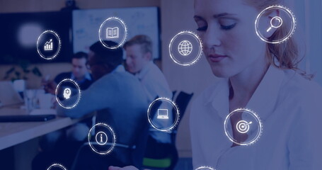 Poster - Image of business icons over caucasian businesswoman using smartphone over colleagues