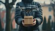 © Zhanna - A drone carrying a small package hovers in front of a person holding it in an urban setting. The image captures the innovation in delivery systems and the integration of technology in everyday life.