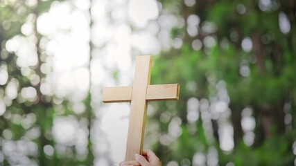 Wall Mural - Friendship hands praying and holding Christian cross for worshipping God at nature bokeh background. Christian, Christianity, Religion copy space background. Easter Sunday concept: