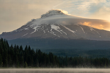 Lenticular clouds over the summit of Mount Hood Oregon, captured during sunrise from Trillium Lake. High quality picture for download.