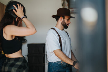 Two individuals gearing up for an outdoor activity. One is wearing a helmet, the other a hat. They appear ready for an adventure.