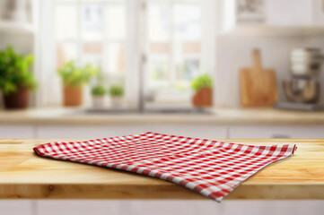 Aufkleber - Red checkered tablecloth covering a wooden table with a blurry kitchen in the background. High quality photo