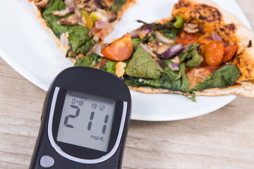 Wall Mural - Glucometer with very high result of sugar level and fresh baked vegetarian pizza. Nutrition during diabetes