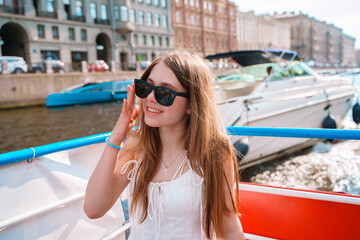 A young tourist girl on a sightseeing boat on the river in St. Petersburg.