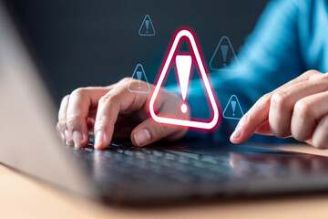 password, safety, spam, cyberspace, hack, danger, sign, caution, virus, problem. A person is typing on a laptop with a red exclamation point on the screen. likely working on a critical task.