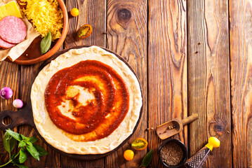 Canvas Print - Raw pizza dough with tomato sauce and basil leaves.