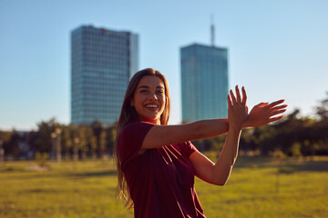 Young woman stretching after exercise and jogging in urban park during sunny summertime day.