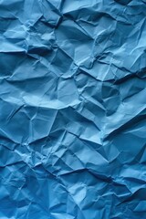 Poster - Crumpled blue paper texture with creased surface. Close-up view of folded and wrinkled paper against dark blue background. Perfect for design, art, or creative projects.