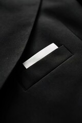 Poster - Black suit jacket close-up shows wrinkled fabric with white pocket neatly folded. Focus on details of blazer texture and design. Perfect for fashion, textile, or lifestyle photography.
