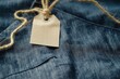 © miss irine - Close-up view of blue jeans with white paper tag on waistband. Fabric background features blue and white pattern. Perfect for fashion, textile, or lifestyle photography.