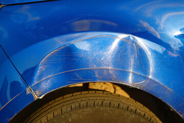 Wall Mural - Car front fender with large dent and visible scratches on blue car body, impact and the need for repair. Parking accident.