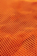 Aufkleber - Vibrant orange fabric close-up shows textured pattern with small holes. Synthetic material appears durable and resistant to wrinkles. Macro shot of jersey texture creates abstract background pattern.