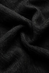 Poster - Close-up view of black fabric with woven texture folded in half. Intricate pattern and shadow create striking visual effect. Fabric appears smooth with subtle wrinkles on gray background.