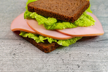 sandwich of black bread with lettuce and mortadella