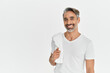 © insta_photos - Happy middle aged man holding shower towel isolated on white studio background. Smiling mature handsome bearded gray-haired male model wearing t-shirt looking at camera. Portrait.