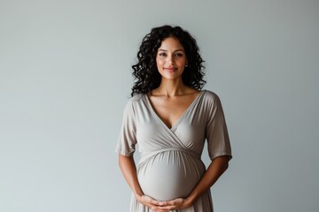 portrait of a happy smiling pregnant indian woman on the light grey background, concept of motherhoo