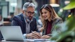 © The Little Hut - Team of diverse partners mature Latin business man and European business woman discussing project on laptop sitting at table in office Two colleagues of professional business people wo : Generative AI