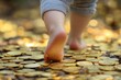© Neda Asyasi - The foot of a child walking on a gold coin. A child walks barefoot