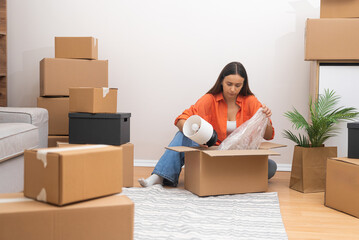 Aufkleber - Attractive female opens large packaging boxes on floor in new house examining integrity of various transported furnishings to new home in countryside