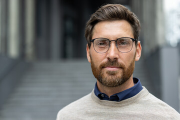 Serious man with beard and glasses using phone outdoors. Depicts professionalism, focus, and determination. Perfect for business, communication, and modern lifestyle concepts.