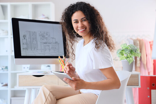 Female African-American graphic designer working with tablet computer in office