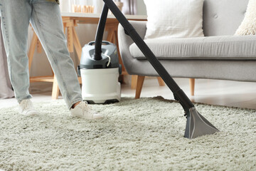 Wall Mural - Woman cleaning carpet with vacuum cleaner at home