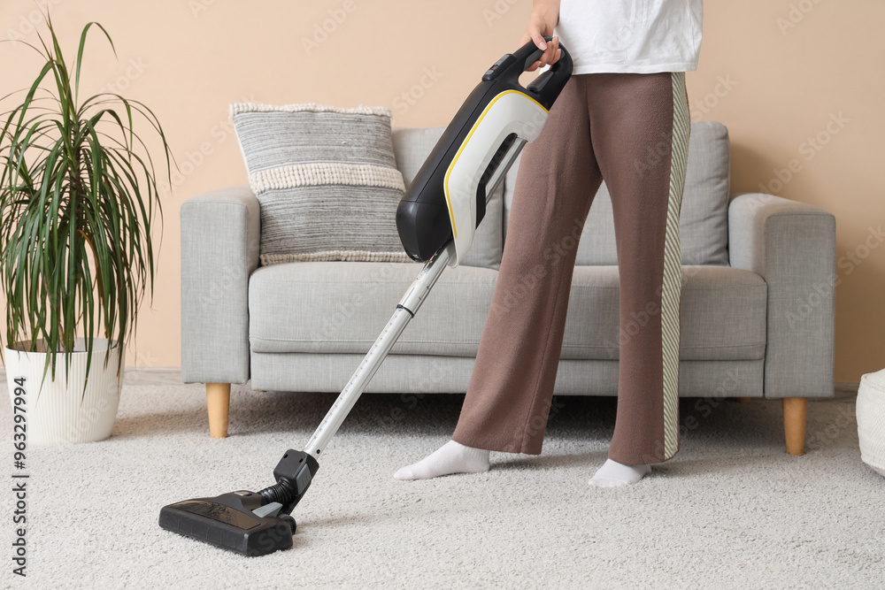 Woman cleaning carpet with vacuum cleaner at home