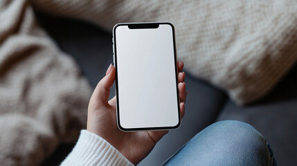 Poster - Woman holding smartphone with blank screen indoors, cozy sweater and jeans, mobile app mockup