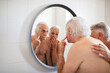 © Marko Geber - Elderly couple examining their skin in bathroom mirror