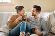 © Chanelle2000/peopleimages.com - Relax, coffee or happy couple laughing on sofa with smile or love in house for care, latte and bonding. Apartment, break and people drinking tea beverage on couch together to chill in lounge in Spain