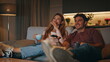 © stockbusters - Married couple resting couch together. Smiling husband switching tv channels